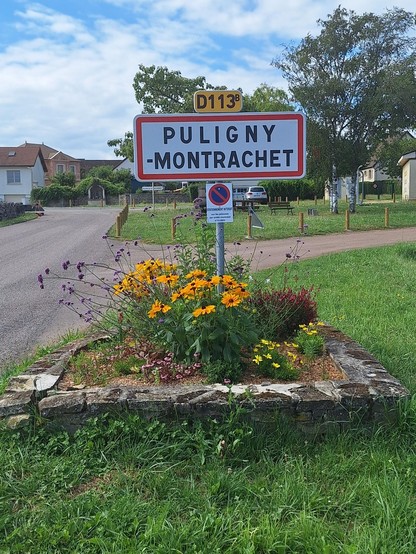 Puligny montrachet panneau d'entrée de village sur une base fleurie